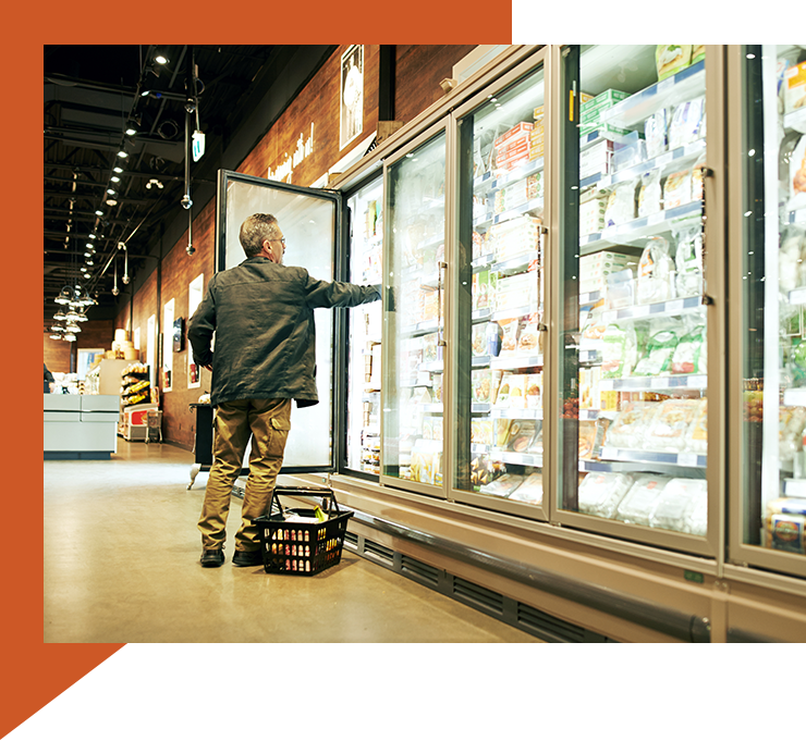 A person opening a grocery store refrigerator door, showcasing an application where the MPS refrigerant gas sensor can be utilized. The image illustrates a common scenario in which refrigeration systems are accessed for maintenance or stocking, highlighting the importance of monitoring for refrigerant leaks to ensure food safety and system efficiency.
